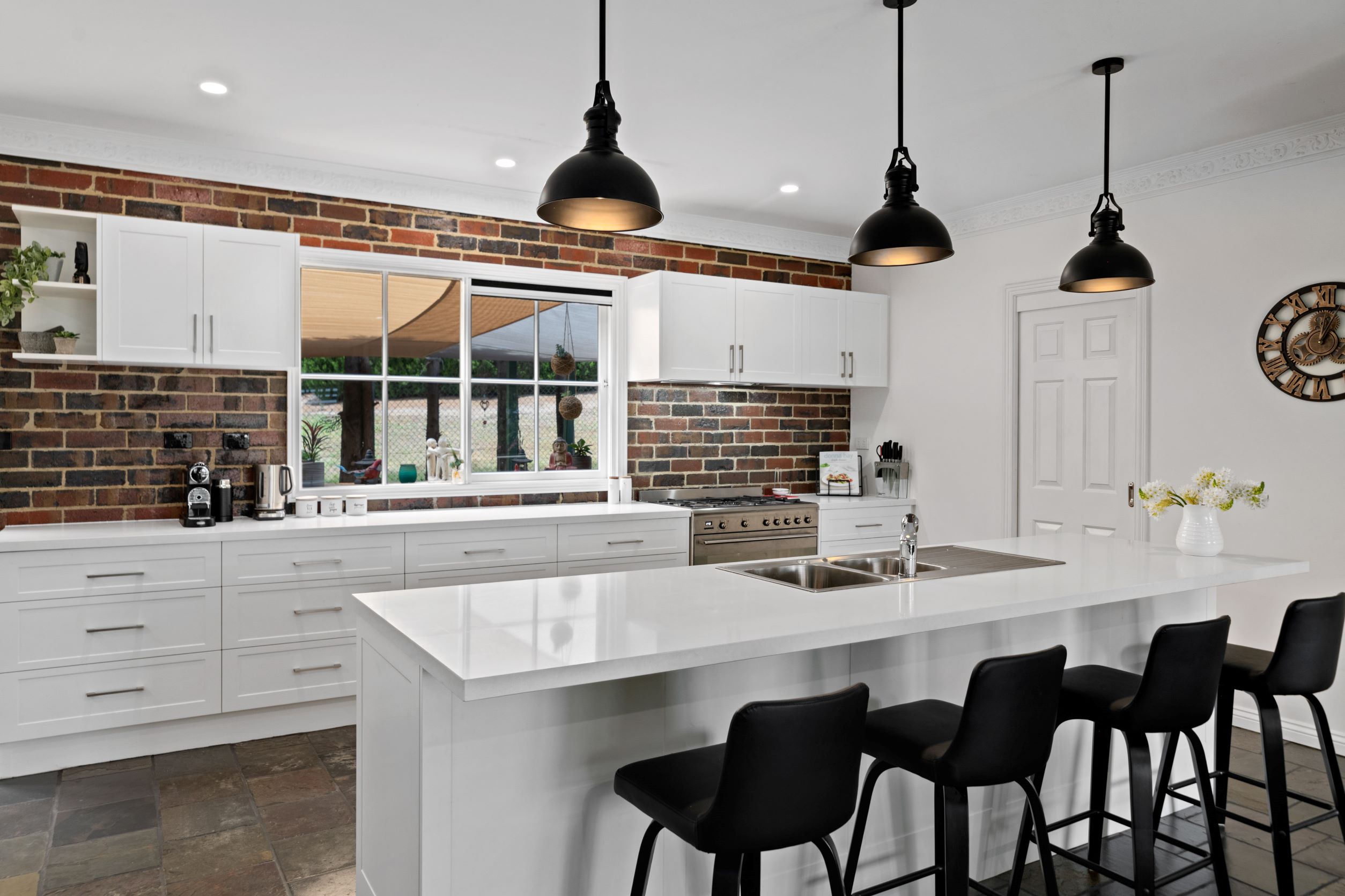 White island bench with a waterfall stone benchtop and four bar stools in a modern Kitchens U Build kitchen
